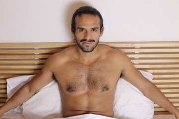 Attractive Hispanic man shirtless in bed 