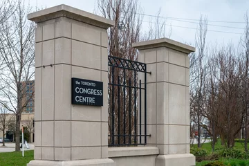 Fotobehang Toronto, Ontario, Canada-June 2022:The gates to Toronto Congress Center. Large limestone square pillars with black wrought iron fencing between the columns. There are trees behind the gate with grass © Dolores  Harvey