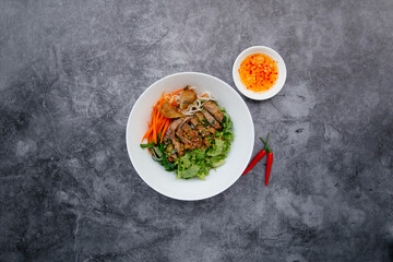 Fried Roll Noodle With BBQ Pork, fish sauce and salad served in bowl isolated on dark grey background top view of japanese food