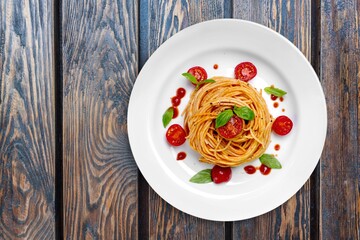 Italian  pasta spaghetti bolognese with tomatoes, cheese and fresh basil in a plate.