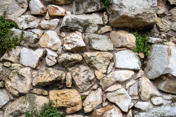 Remains of an old wall. Ancient stonework. Lots of cobblestones on the grass. Ancient remains of...