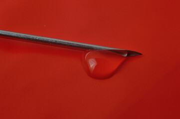 Syringe needle and a drop of a transparent substance. close-up