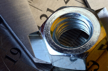 Accurate measuring tool caliper and metal ruler lie in place with nuts. close-up.