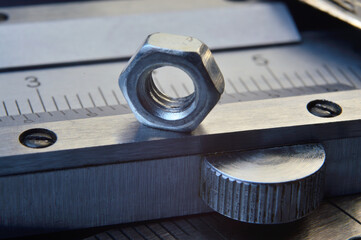 Accurate measuring tool caliper and metal ruler lie in place with nuts. close-up.
