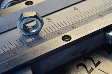 Accurate measuring tool caliper and metal ruler lie in place with nuts. close-up.