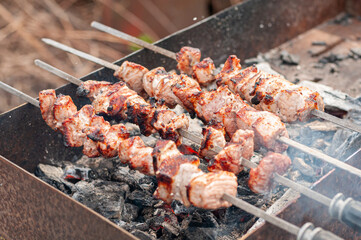Marinated shashlik preparing on a barbecue grill over charcoal. Shashlik or Shish kebab popular in...