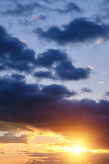 Thunderclouds with breaking rays sun at sunset.