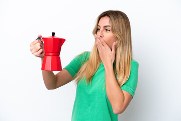 Young Uruguayan woman holding coffee pot isolated on white background with surprise and shocked facial expression