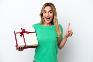 Young Uruguayan woman holding a gift isolated on white background pointing up a great idea