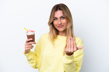 Young Uruguayan woman holding Frappuccino isolated on white background inviting to come with hand. Happy that you came