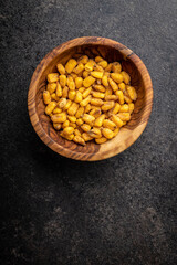 Roasted salted corn snack in bowl on black table.