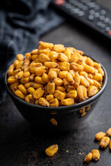 Roasted salted corn snack in bowl on black table.