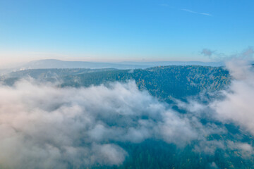 Aerial view of the foggy morning at the green mountains, clear blue sky. 