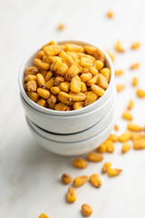 Roasted salted corn snack in bowl on white table.