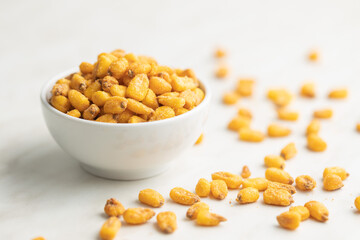 Roasted salted corn snack in bowl on white table.