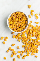 Roasted salted corn snack in bowl on white table.