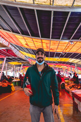 Young, bearded, handsome and happy guy with green jacket and red drink bottle in the public 'Mercado Fluvial' (river market), Valdivia, Chile