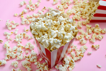 Full box of popcorn. Airy popcorn in a paper cup and scattered on the table.