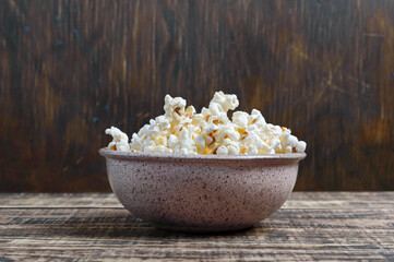 Fresh popcorn in a bowl on a wooden background. Rustic style.