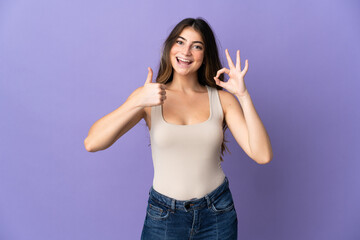 Young caucasian woman isolated on purple background showing ok sign and thumb up gesture