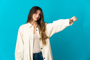 Young caucasian woman isolated on blue background giving a thumbs up gesture