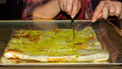 The woman hands cutting Katmer. The katmer traditional dessert from Turkey. The famous traditional dessert from Gaziantep, Turkey. 