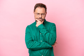 Fototapeta premium Middle age caucasian man isolated on pink background having doubts
