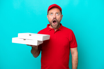 Pizza delivery man with work uniform picking up pizza boxes isolated on blue background looking up...