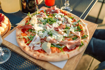 Served dinner table with pizza with Mozzarella cheese, ham, pepper, olive, meat on grey wooden board background in pizzeria or restaurant.