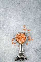 Top view of Himalayan pink salt in a spoon on a grey background