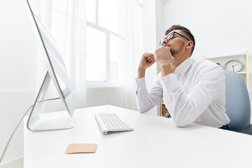 Obraz premium manager in a white shirt sits at a computer with a phone technologies