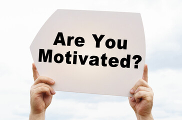 Against the background of the sky in the hands of a man is a sign with the inscription - Are You Motivated
