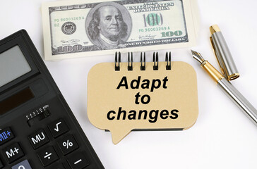 On a white surface, a calculator, dollars, a pen and a sign with the inscription - Adapt to Changes