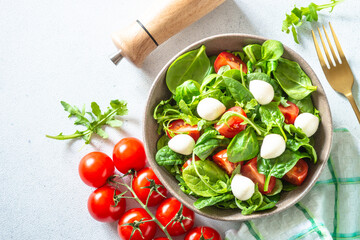 Green salad with fresh leaves, tomatoes and mozzarella. Top view, copy space.