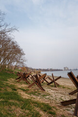 Military anti-tank czech hedgehogs on river bank. Metallic barricade or obstacle for defense. War...