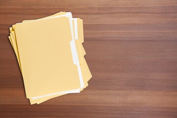 Paper file with documents on wooden table, top view. Space for text