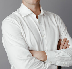 Close up of crossed arms of a businessman on a gray background