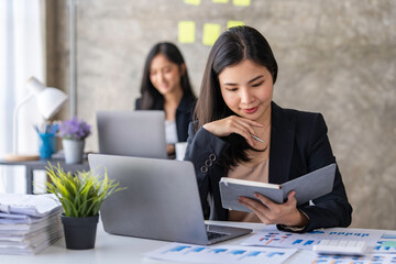 Young Asian businesswoman working online with laptop computer while sitting in office. Self-employed and freelance worker business activity concept