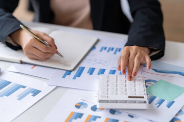 Fototapeta premium Close up Business woman using calculator and laptop for do math finance on wooden desk in office and business working background, tax, accounting, statistics and analytic research concept