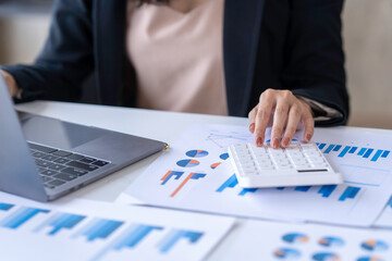 Obraz premium Close up Business woman using calculator and laptop for do math finance on wooden desk in office and business working background, tax, accounting, statistics and analytic research concept