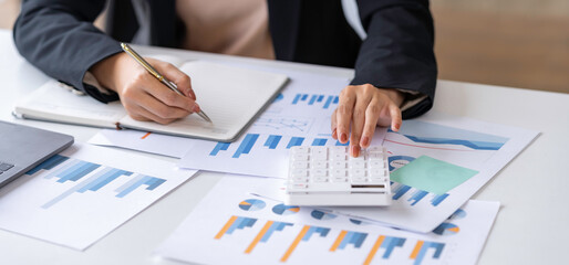 Close up Business woman using calculator and laptop for do math finance on wooden desk in office...