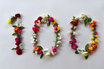 Number hundred made of natural flowers and leaves. Floral numerical concept. Creative idea for spring, summer, birthdays and anniversaries.