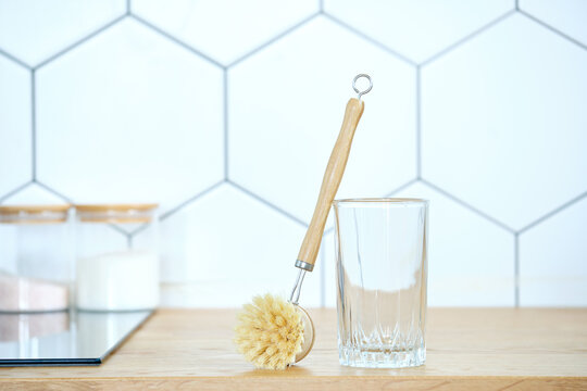 eco-friendly dishwashing brushes with organic bristles and a wooden handle next to a glass on the kitchen table. The concept of minimum consumption, zero-waist