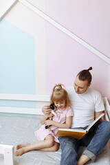 Dad is reading a book with his daughter.