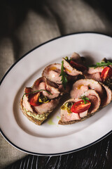 Appetizing bruschetta with ham and tomatoes on a dark wooden background