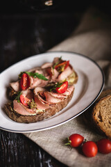 Appetizing bruschetta with ham and tomatoes on a dark wooden background