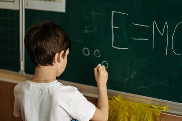 The concept of a simple letter of a child at school. The first grader writes on the blackboard. Development of a genius child