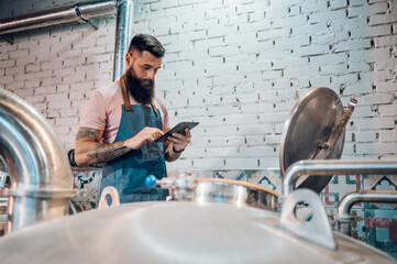 Men working at brewery and using a tablet application for fermentation process