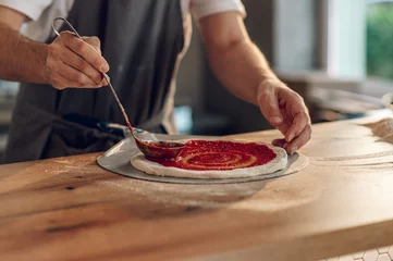 Keuken spatwand met foto Man worker in a pizza place placing ingredients on pizza dough © Zamrznuti tonovi
