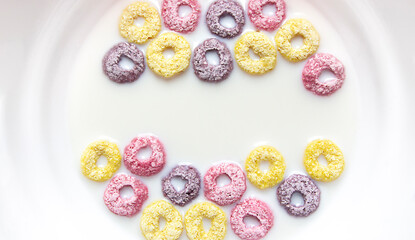 in a plate of milk with multi-colored rainbow rings of cereals. healthy food, fast breakfast. copy space